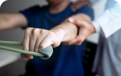 Physical therapist supporting patient's forearm during resistance band exercise.