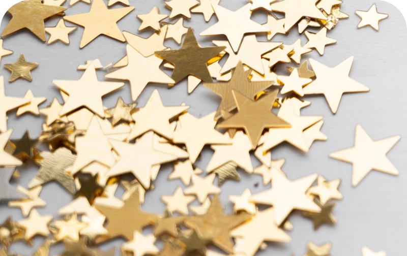 Scattered gold star confetti on a gray surface