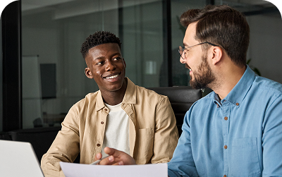Two men in an office reviewing documents and smiling
