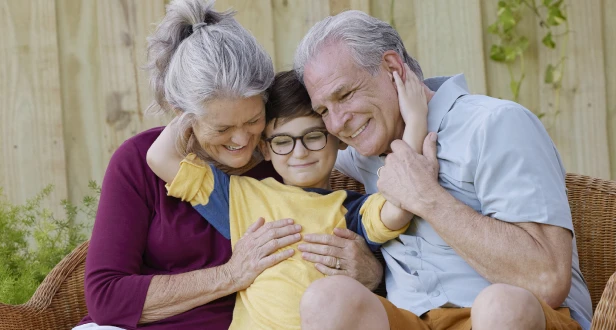A loving family moment with two adults and a child sitting together in a cozy wicker chair