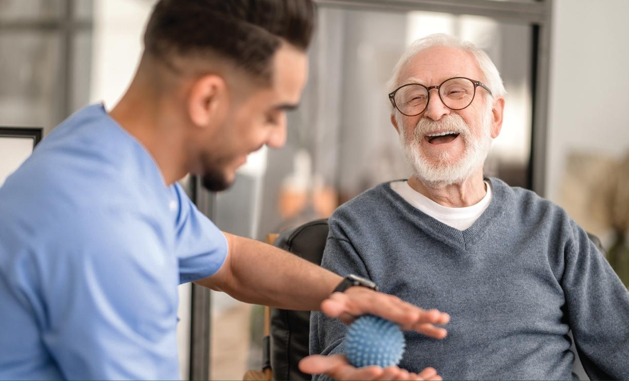 Caregiver teaching blue stress-ball exercise to elderly patient