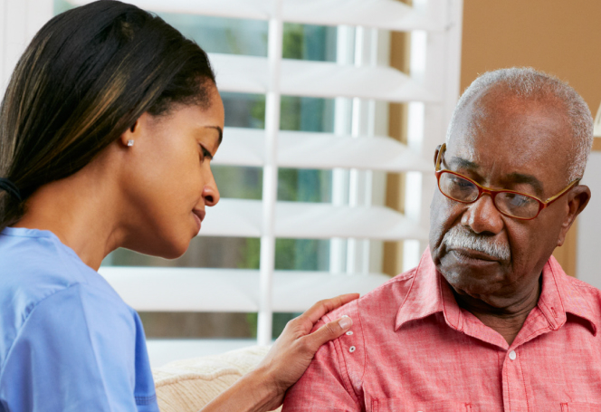 A nurse in blue scrubs gently checks an elderly man's blood pressure