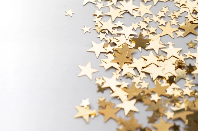Scattered gold star confetti on a gray surface