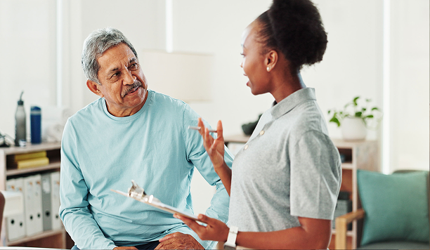 A healthcare professional discusses information with an older patient in a bright, modern office setting