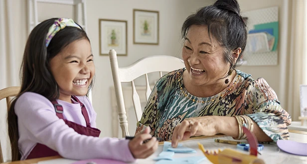 A woman and a child engage in a creative activity together, surrounded by art supplies in a cozy, well-lit room