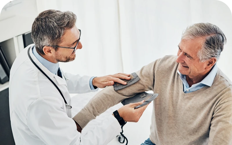 A doctor takes a patient's blood pressure during a consultation in a well-lit medical office setting