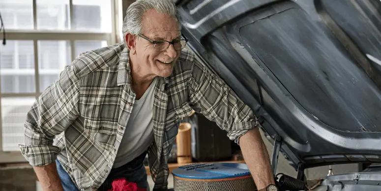 A old man opened a car bonnet and looking on it